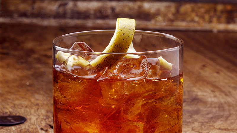 Glass of cocktail garnished with Citrus Twist