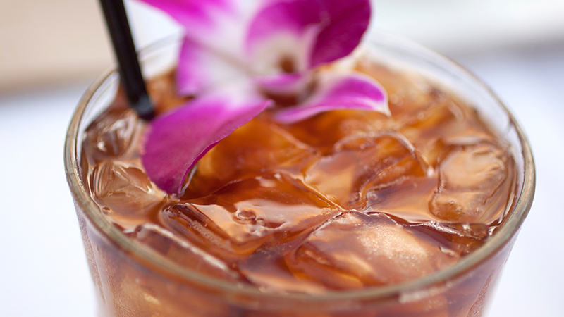 Glass of cocktail garnished with pink flower