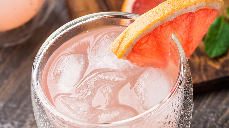 Glass of cocktail garnished with grapefruit wedge