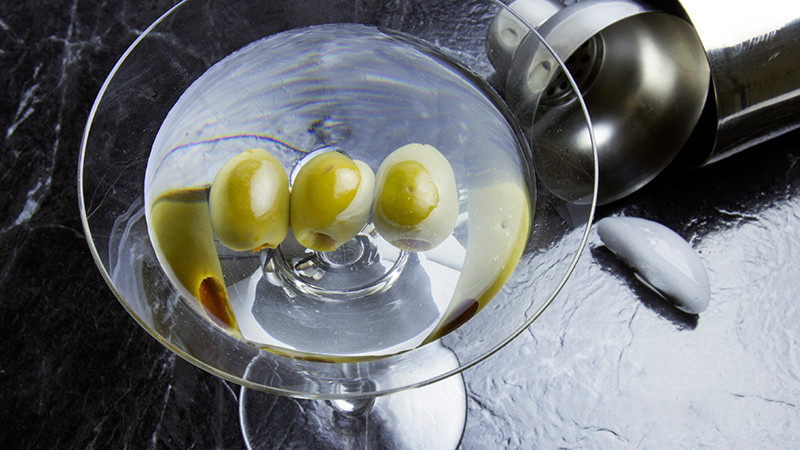 Glass of cocktail garnished with olives