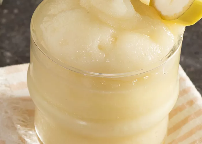 Glass of Banana ‘Nana Daiquiri garnished with banana slice on white cloth