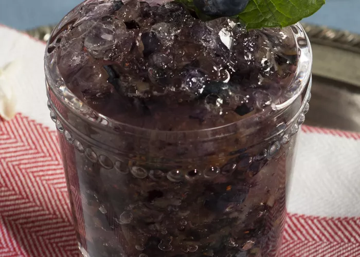 Glass of Blue Stallion Julep garnished with blueberry and mint leaves 