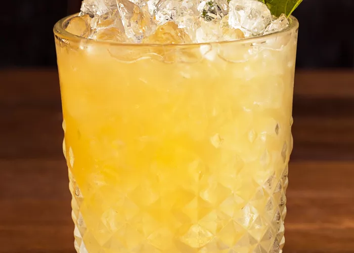  A Glass of Double Oak Whiskey Smash on coaster with crushed ice and garnished with mint leaves