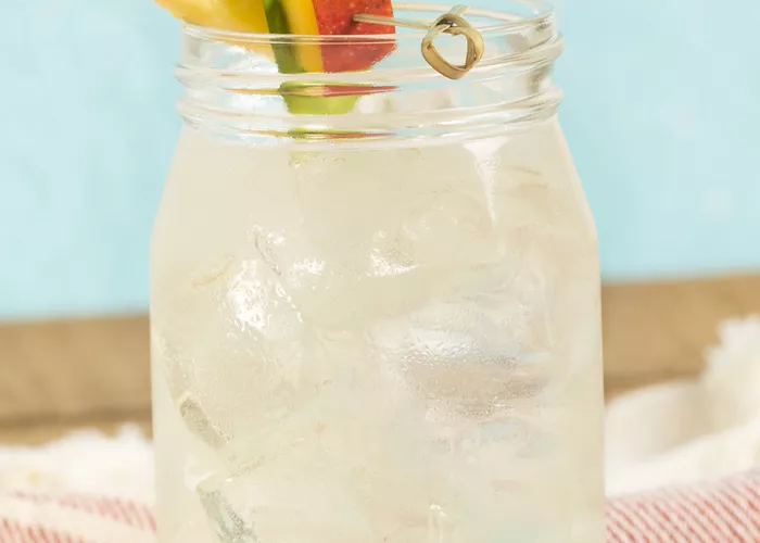  Cruzan® Confusion served in a glass with pineapple, pineapple leaves, and mango on a table with a cloth.