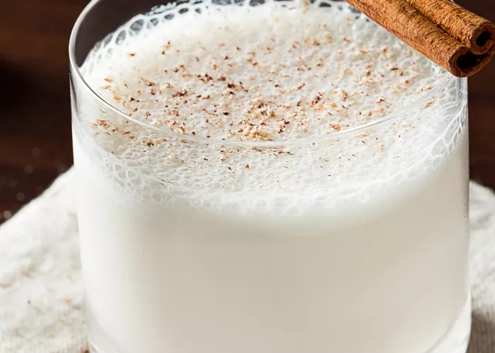 Glass of Bourbon Milk Punch on a napkin, garnished with a cinnamon stick.