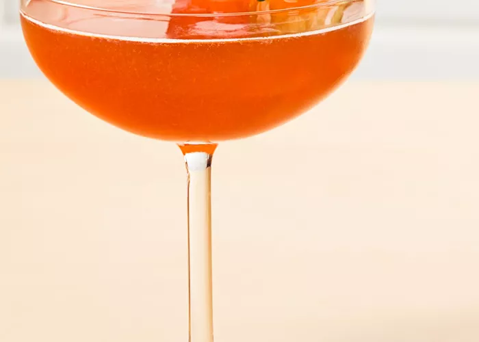 Glass of Melon Berry Mist garnished with strawberry and cucumber wheel on coaster