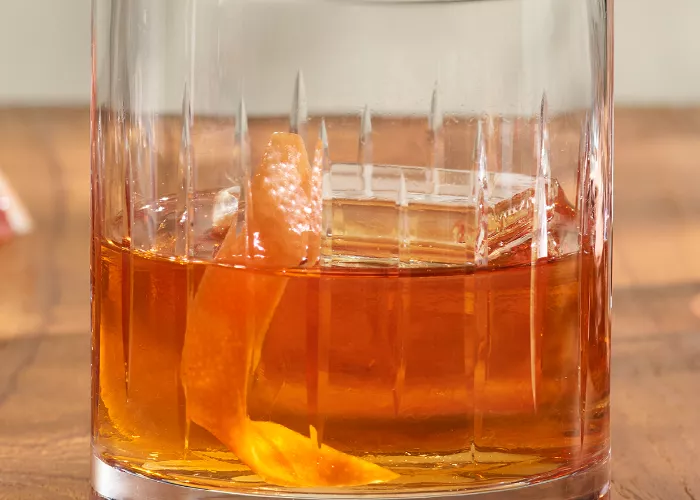 Glass of Basil Hayden's® Golden Hour with ice cube and orange peel