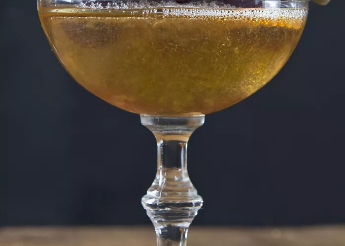 Glasses of Bellini Manhattan garnished with cherries on a pick.