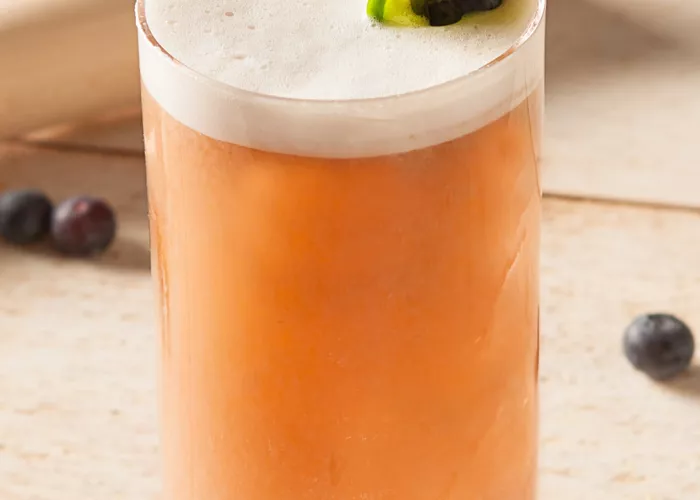 a glass of Blucumber Fizz garnished with cucumber and blueberries