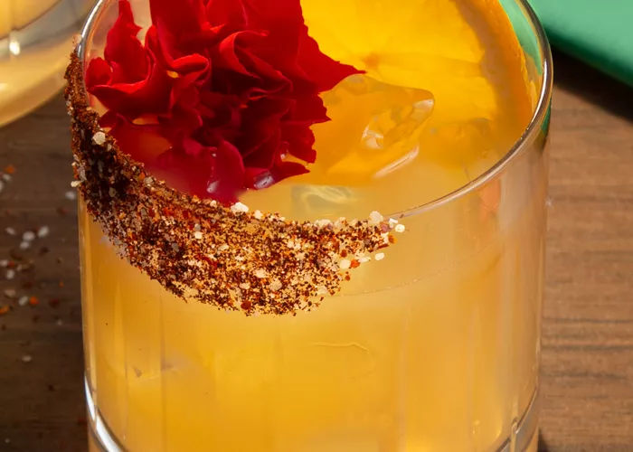 A glass of Don Francisco Margarita garnished with Orange Wheel and Edible Marigold 