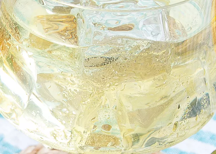 Glass of Cruzan® Daiquiri garnished with orange wedge alongside some half kiwi