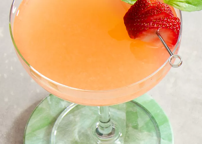 A glass of Japanese Gin Sour garnished with strawberry and mint leaves 