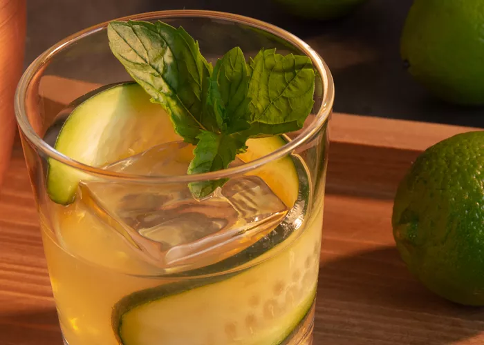 A glass of  Kentucky Made garnished whith cucumber slices and mint leaves 