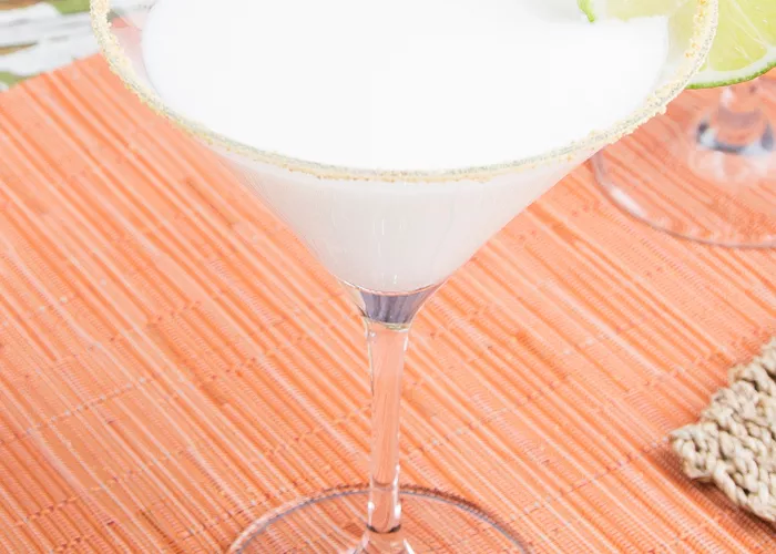 A glass of Key Lime Pie Martini garnished with wheel of lime on rim