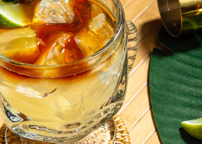 A glass of Mai Tai garnished with Mint Sprig and Lime Wedge 