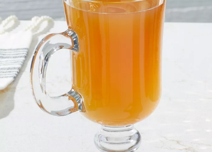 A glass of Maker's Mark® Hot Apple Cider garnished along with  a Cinnamon Stick, Lemon Whee