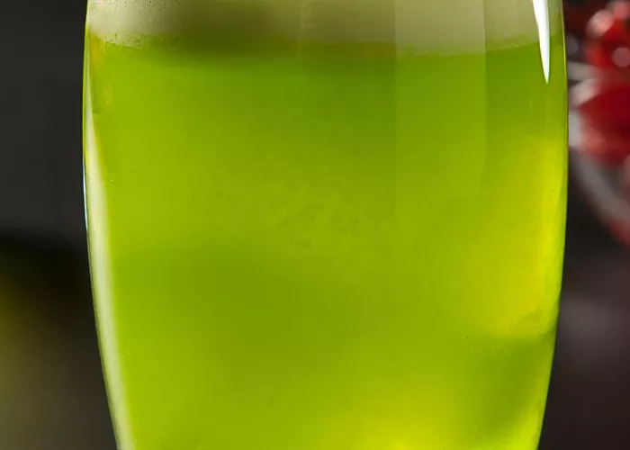 Glass of Fresh Midori® Sour garnished with a cherry.