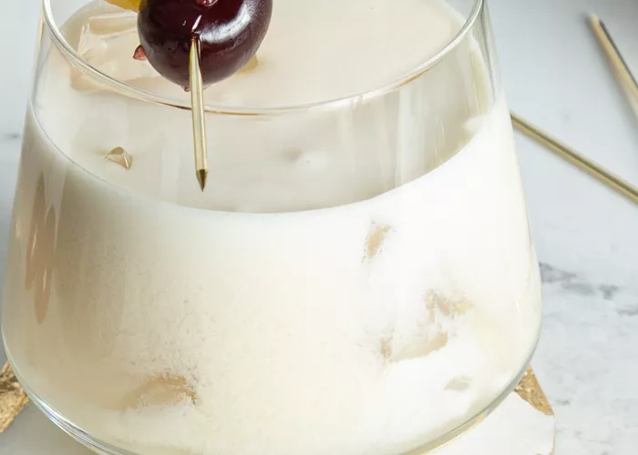 A glass of Piña Colada garnished with Pineapple Slice and Cherries 