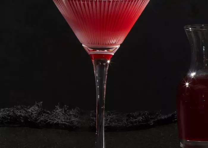 A glass of Pinnacle® Black Widow Martini alongside small bottle of red liquid