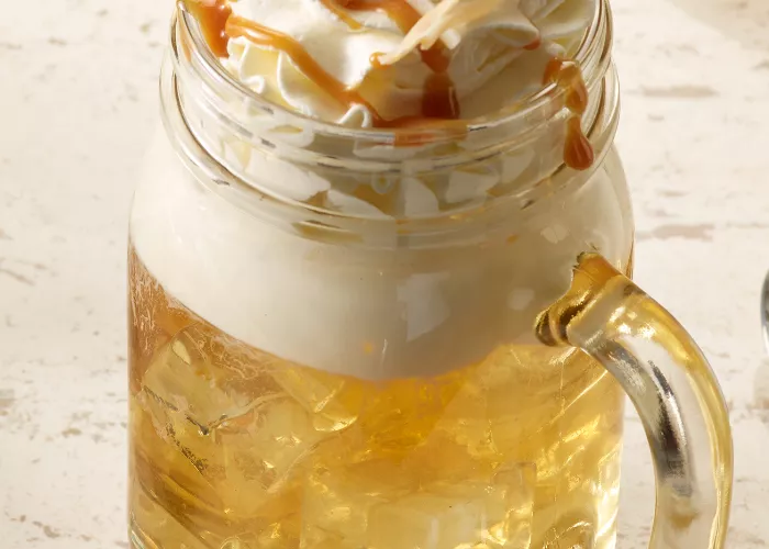 A glass of SQRRL® Top Banana garnished with Whipped Cream and toasted Coconut 