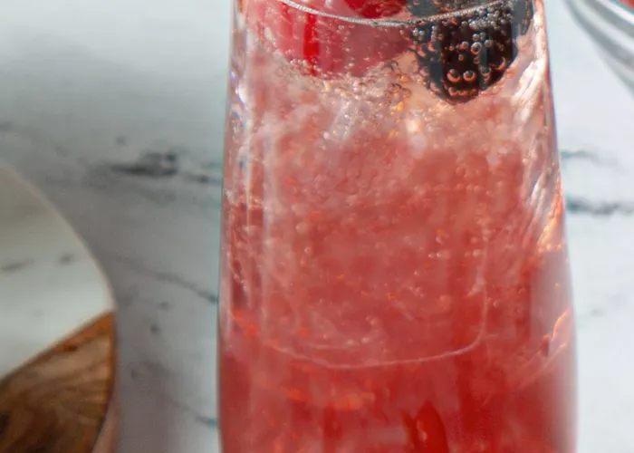 A glass of  Sparkling Berry Sangria garnished with Strawberries and Blueberries 