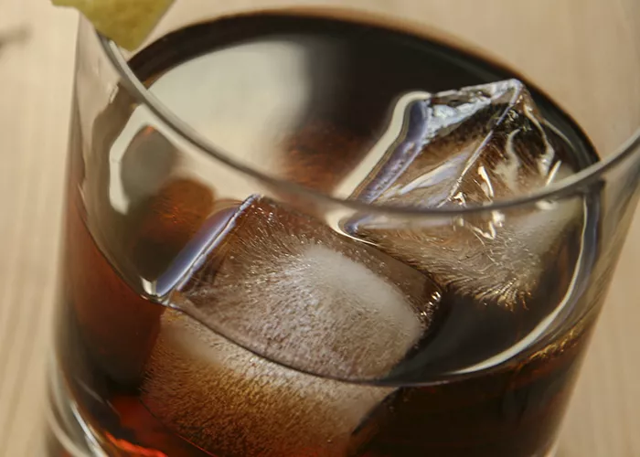 glass filled with black russian and ice cube