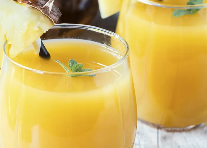Two glass of Planter's Punch garnished with slice of pineapple on rim and a straws