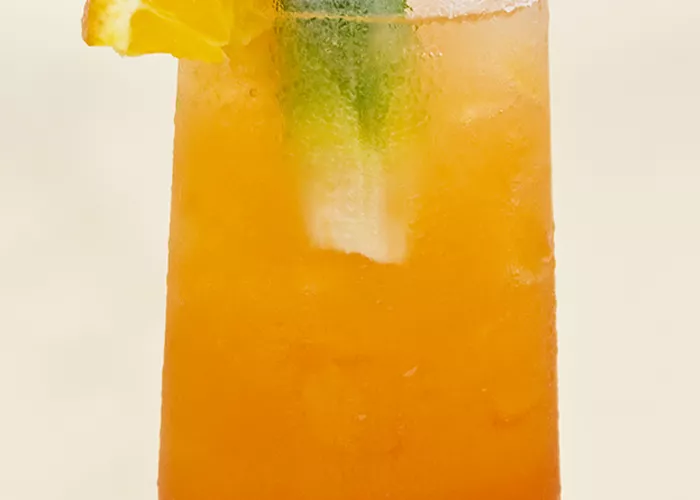 A Glass of Voodoo Hurricane garnished with crushed ice, cherry, orange, lemon, and fruit wedges.