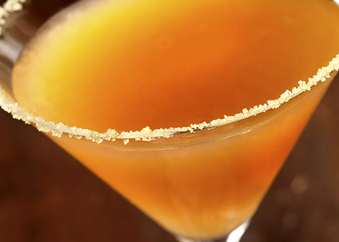 A glass of Autumn-tini with a rim coated in a Sugar/Cinnamon/Cayenne Pepper mix.