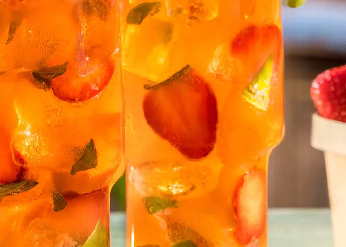 Glass of Basil Berry Mojito garnished with basil leaves and sliced strawberries