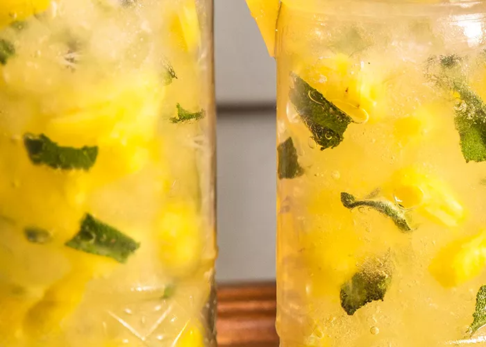 Two glasses of Pineapple Crush garnished with crushed ice and pineapple slice and a leaf