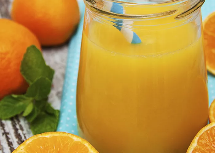 A mug glass of Smashin' Passion along with couple of oranges, some halved oranges, few mint leaves. And a straw in the mug .