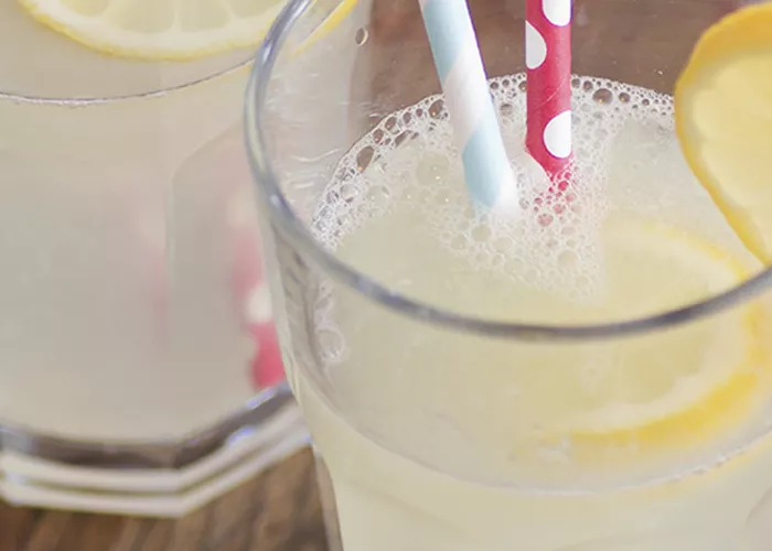 Two glasses of Weekenders' Punch garnished with lemon slices and a couple of strawss inside.