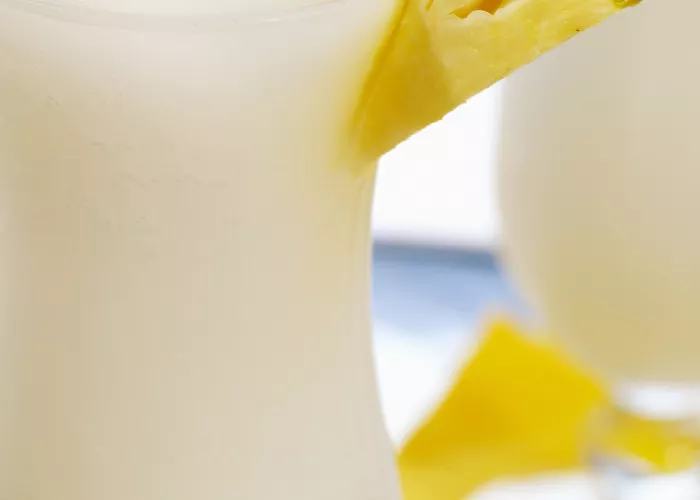 A glass of Apple Colada garnished with a slice of pineapple on a rim of glass