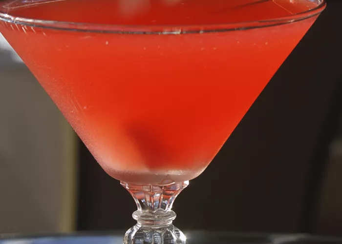 A glass of Cran-Apple Martini with a cocktail pick