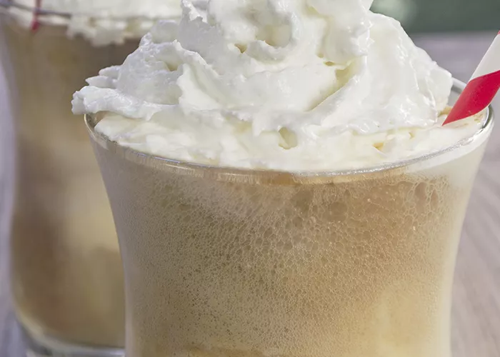 Two glass of Root Beer Freeze with  straws and garnished with whipped cream.