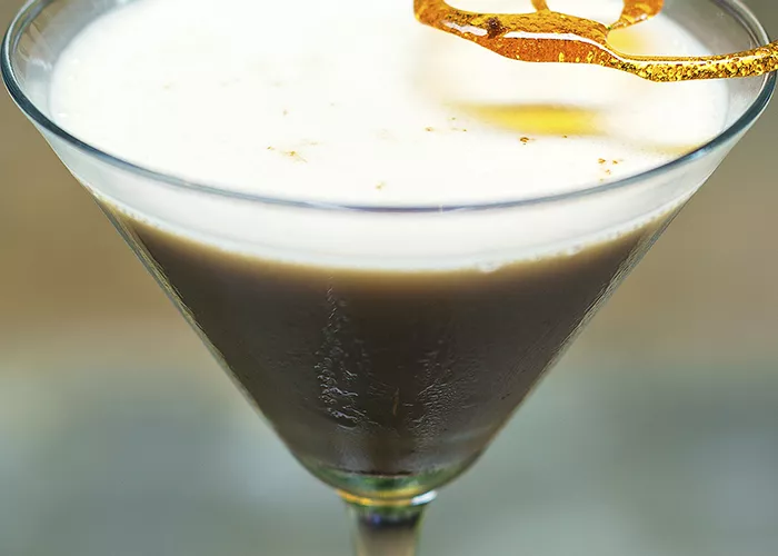 A glass of toffee drop martini garnished with spun sugar 