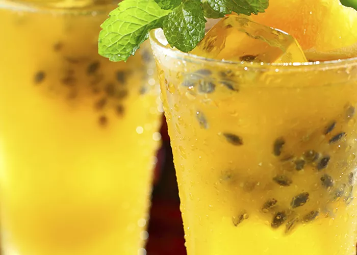 Two glasses of The Summer Friday garnished with blood orange slice, mint leaves and ice cubes .