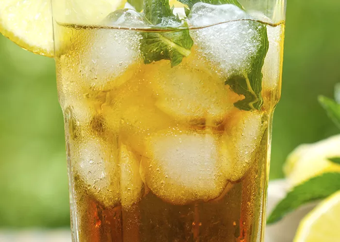 A glass filled with apple highball and lemon with mint
