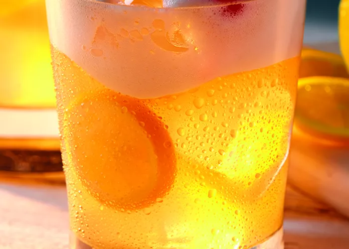 a glass of borubon sour with a leaf on top of it