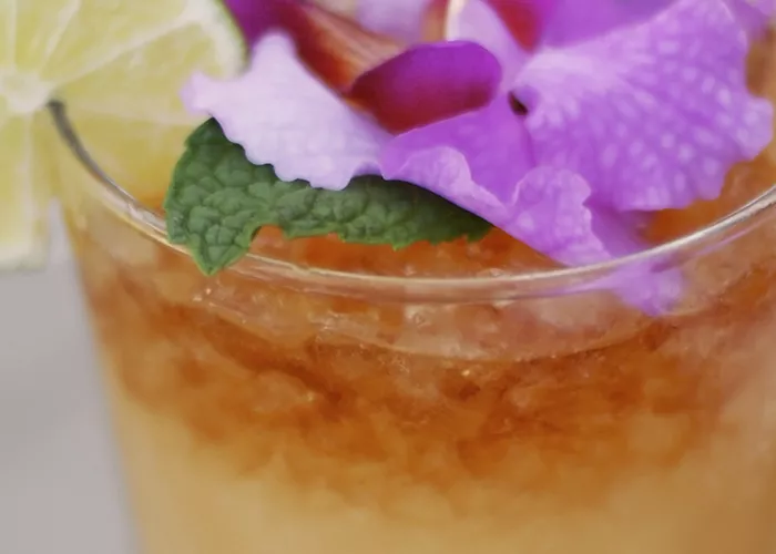 a glass of Kentucky Joe garnished with a slice of lime and flowers