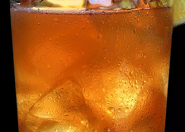 Glass of Maker's Mark® Mojito with ice cubes, garnished with a sugar rim and a lemon wheel.