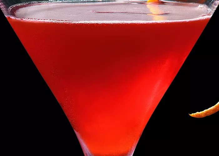 Glass of The Unnecessary Noise garnished with strip of orange zest.
