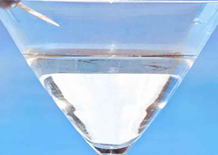 A cocktail glass of Sunset Martini garnished with cherries on a cocktail pick