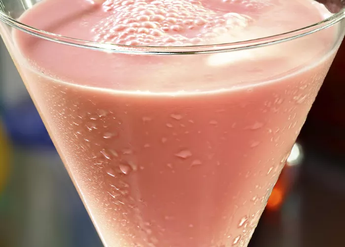 A martini glass of Vanilla Cream Berry-Tini garnished with raspberries.