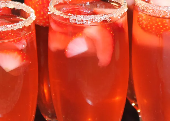 A glass of Sauza® strawsberry Sparkler, garnished with a wedge of lime and sugar on the rim of the glass
