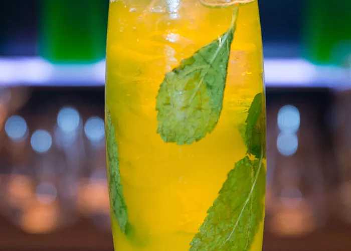 a glass with a Midori® Jim and Ginger garnished with mint leaves and straw