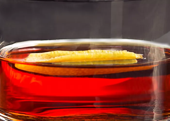 A glass of Hornitos® Black Barrel® Tequila Manhattan placed on the silver tray, garnished with orange peel.