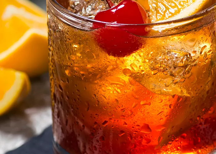 a glass of Bourbon Cider Cocktail with orange slices and a cherry on top