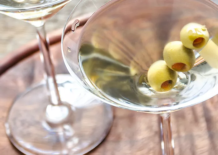Two glasses of Dirty Martini garnished with olives